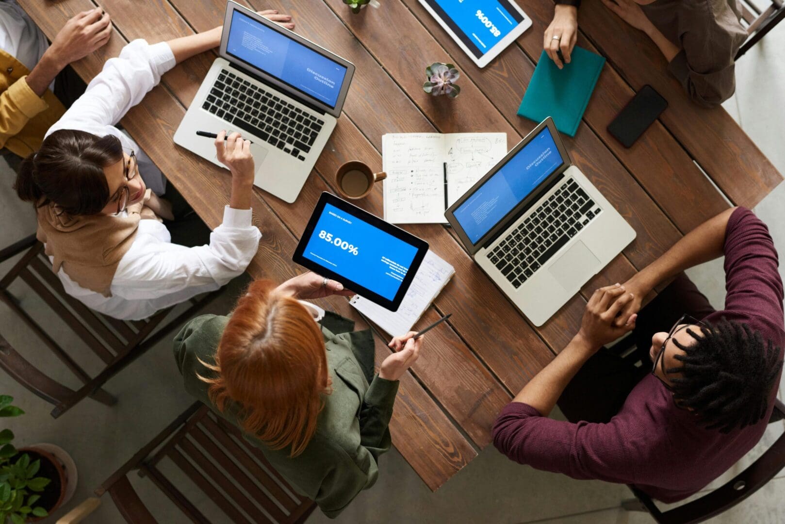 A group of people sitting around a table with laptops.